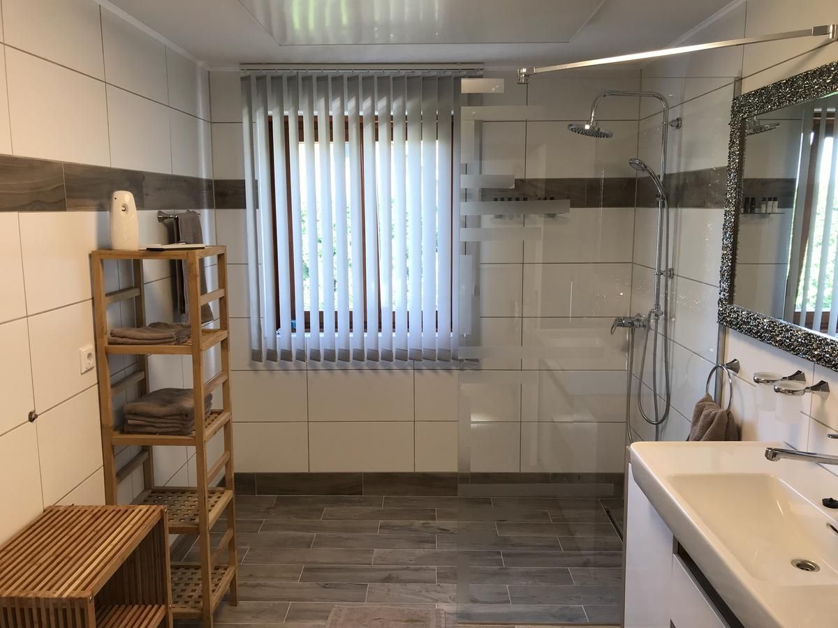 Modernes Badezimmer mit Dusche, Waschbecken, Spiegel und Regal.