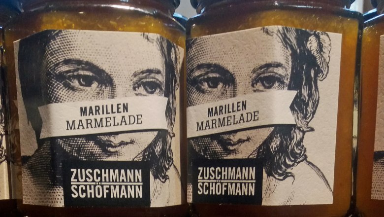 Zwei Gläser Marillenmarmelade mit Etiketten, die ein Gesicht zeigen.