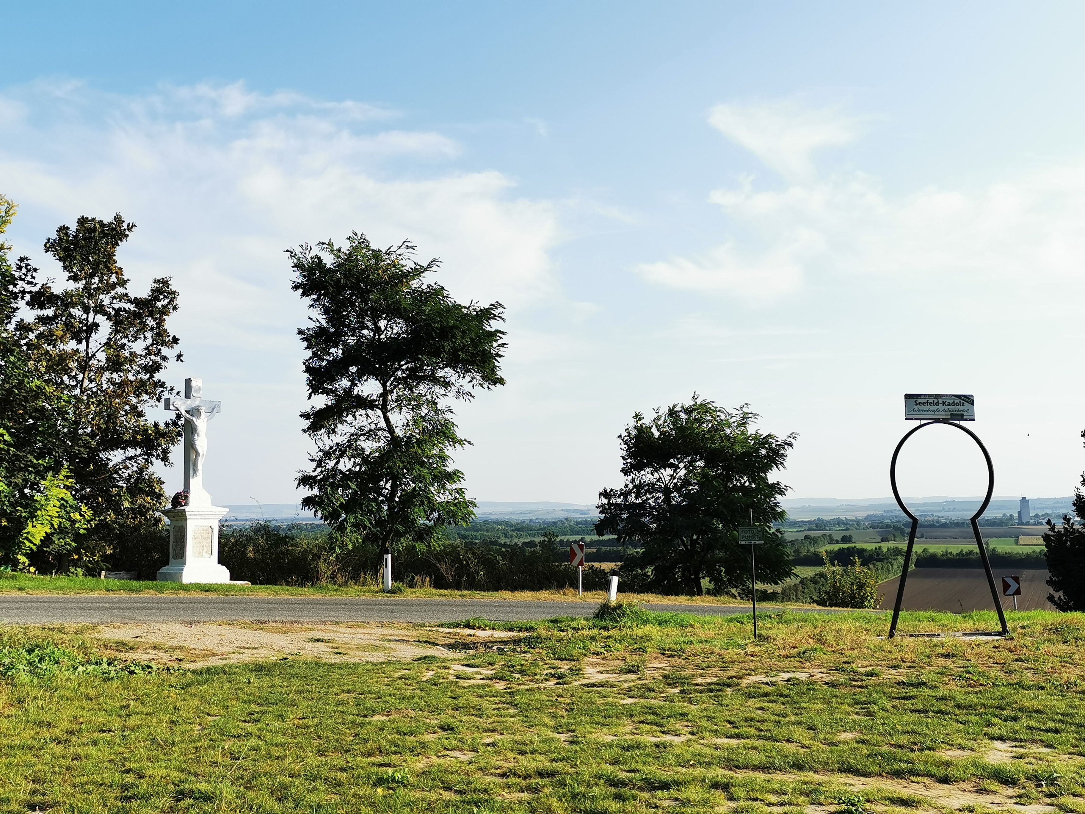 Landschaft mit Kreuz und Seefeld-Kadolz Schild.
