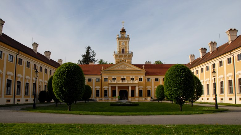 Schloss Jaidhof mit gelber Fassade und Turm, umgeben von gepflegtem Garten.