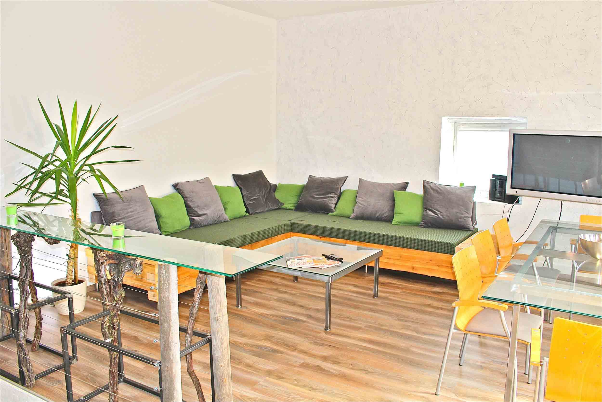 Modernes Wohnzimmer mit Ecksofa, Glastisch und Fernseher.