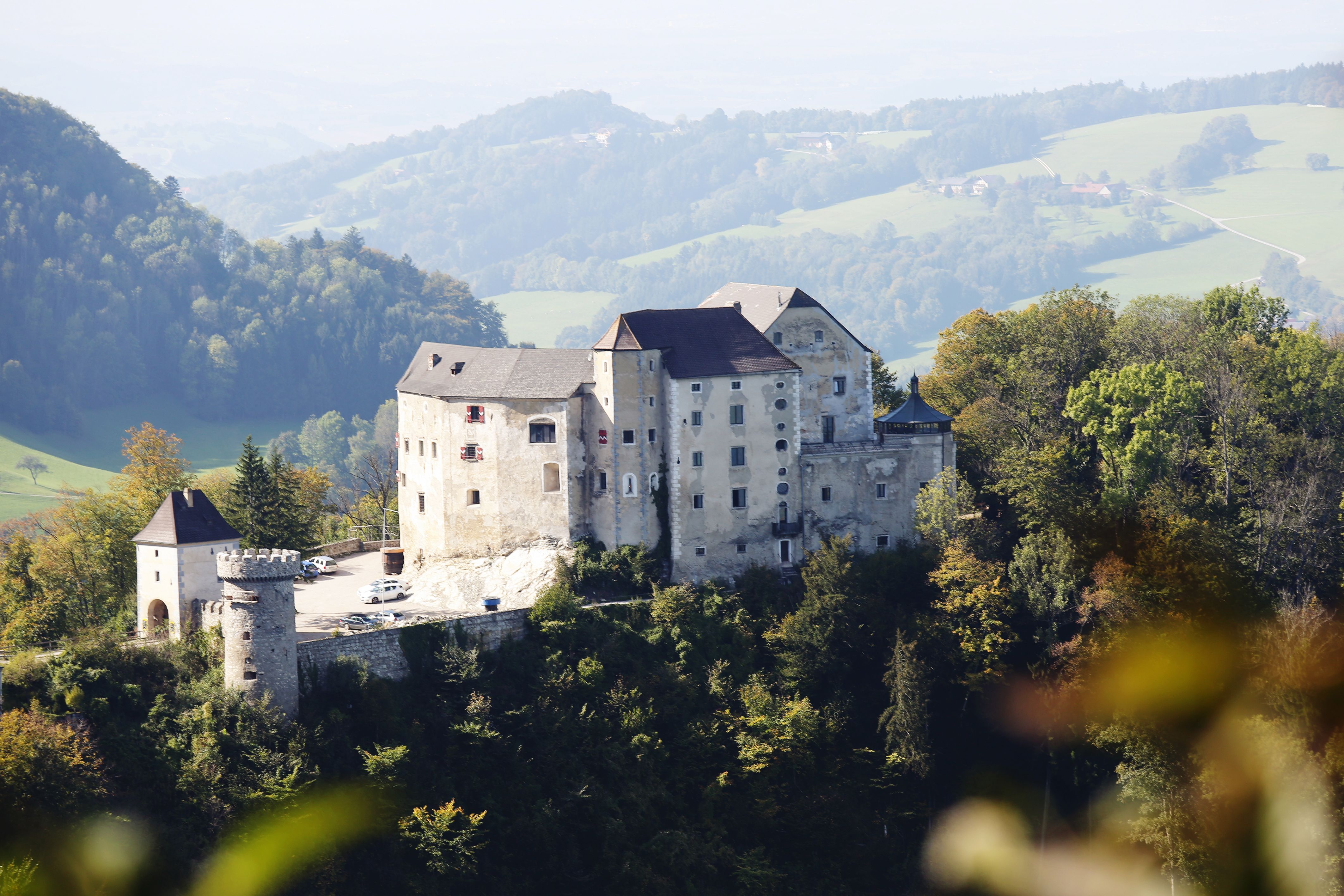 Burg Plankenstein auf einem Hügel mit umliegenden Wäldern und Hügeln im Hintergrund.