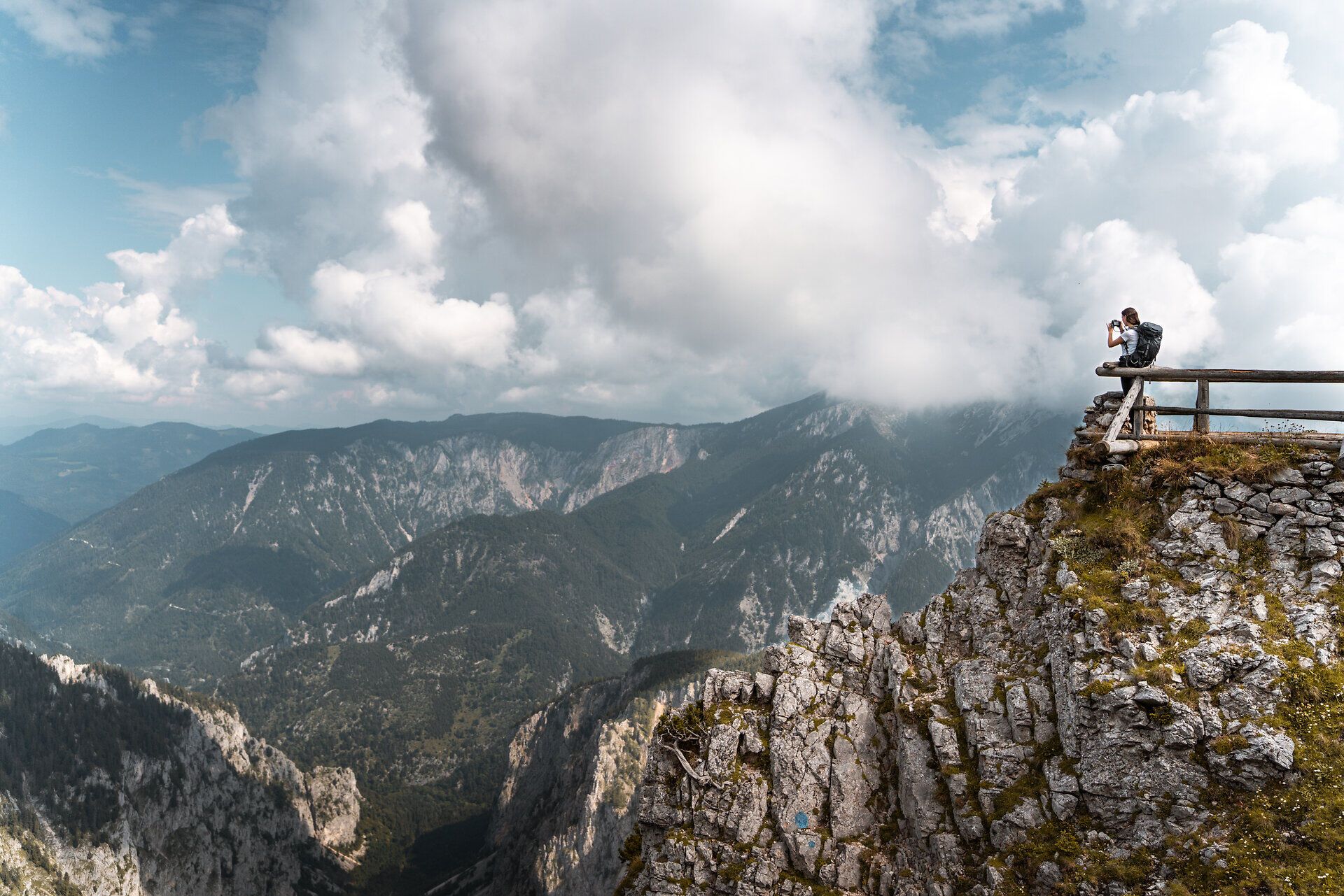 Blick auf eine tiefe Schlucht mit steilen Felswänden und bewaldeten Bergen im Hintergrund unter klarem Himmel.
