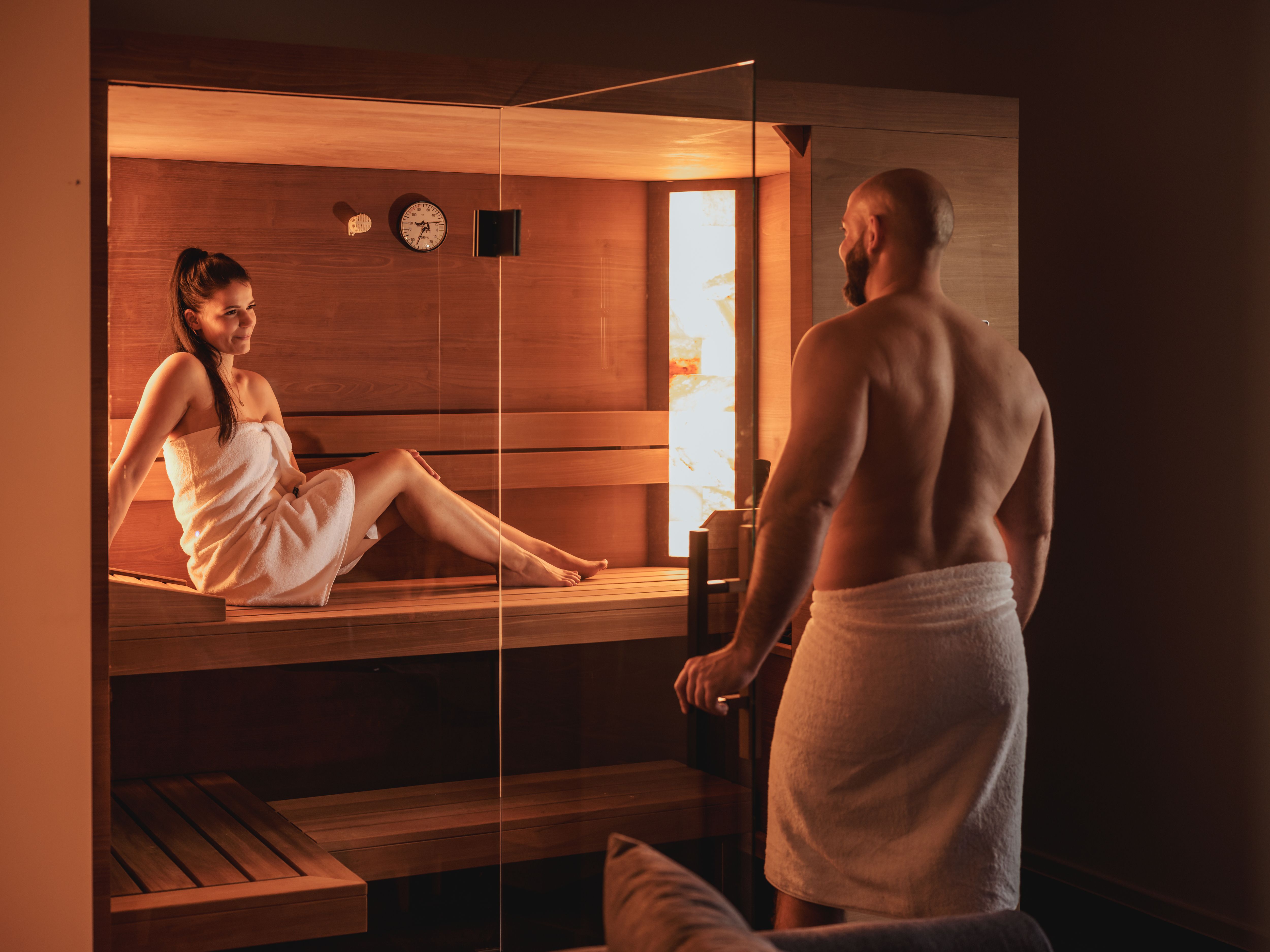 Ein Mann und eine Frau in Handtüchern in einer Sauna.