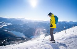 Snowboarder springt über ein gelbes Hindernis im Snowpark Gemeindealpe bei Sonnenschein.