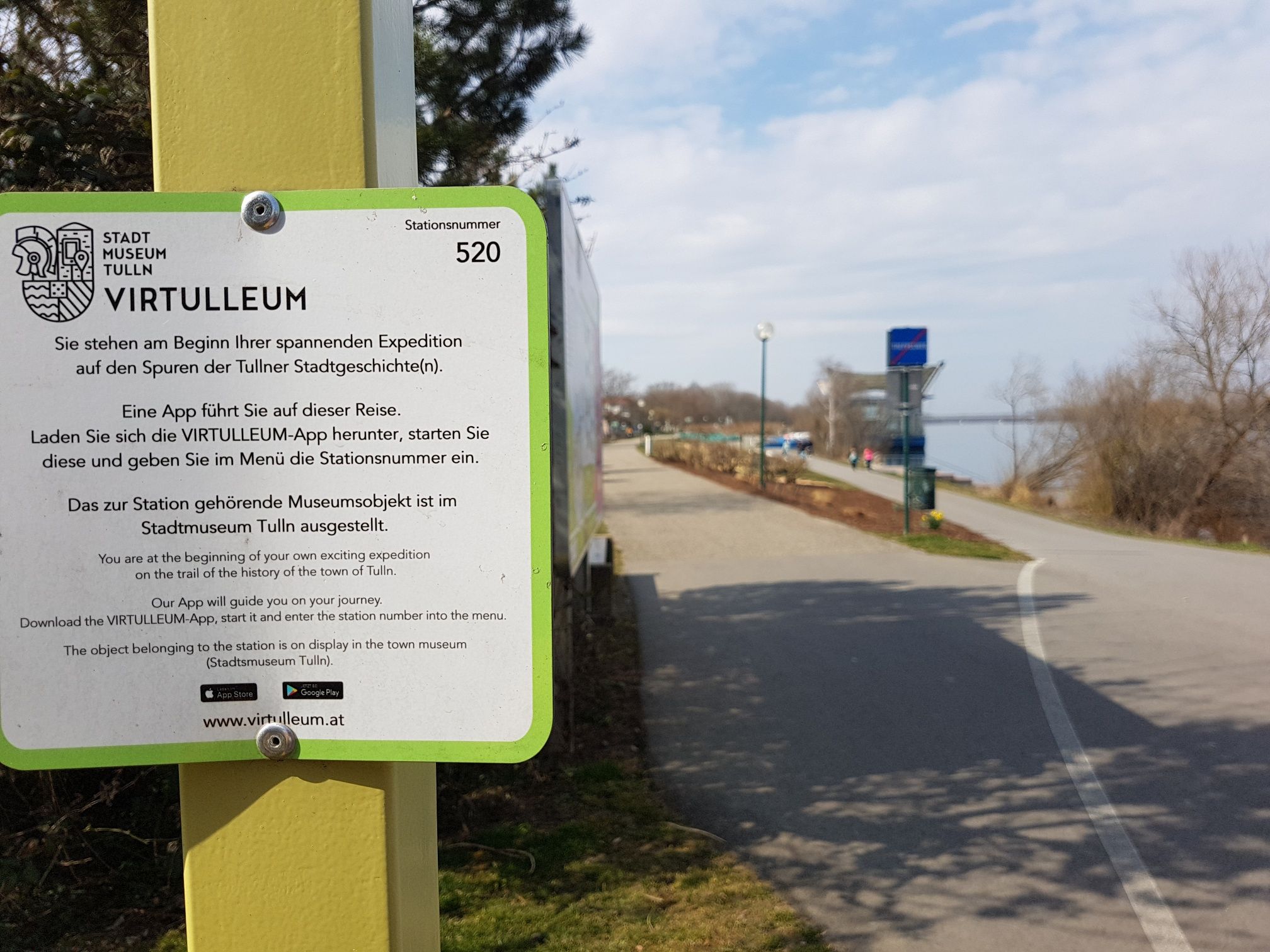 Schild des Virtulleum in Tulln mit Weg im Hintergrund.