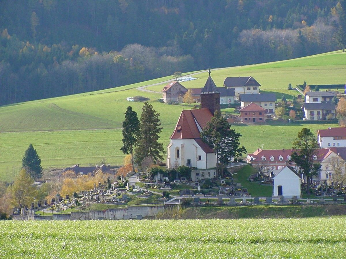 Erasmuskirche in Krumbach mit umliegendem Friedhof und grüner Landschaft.