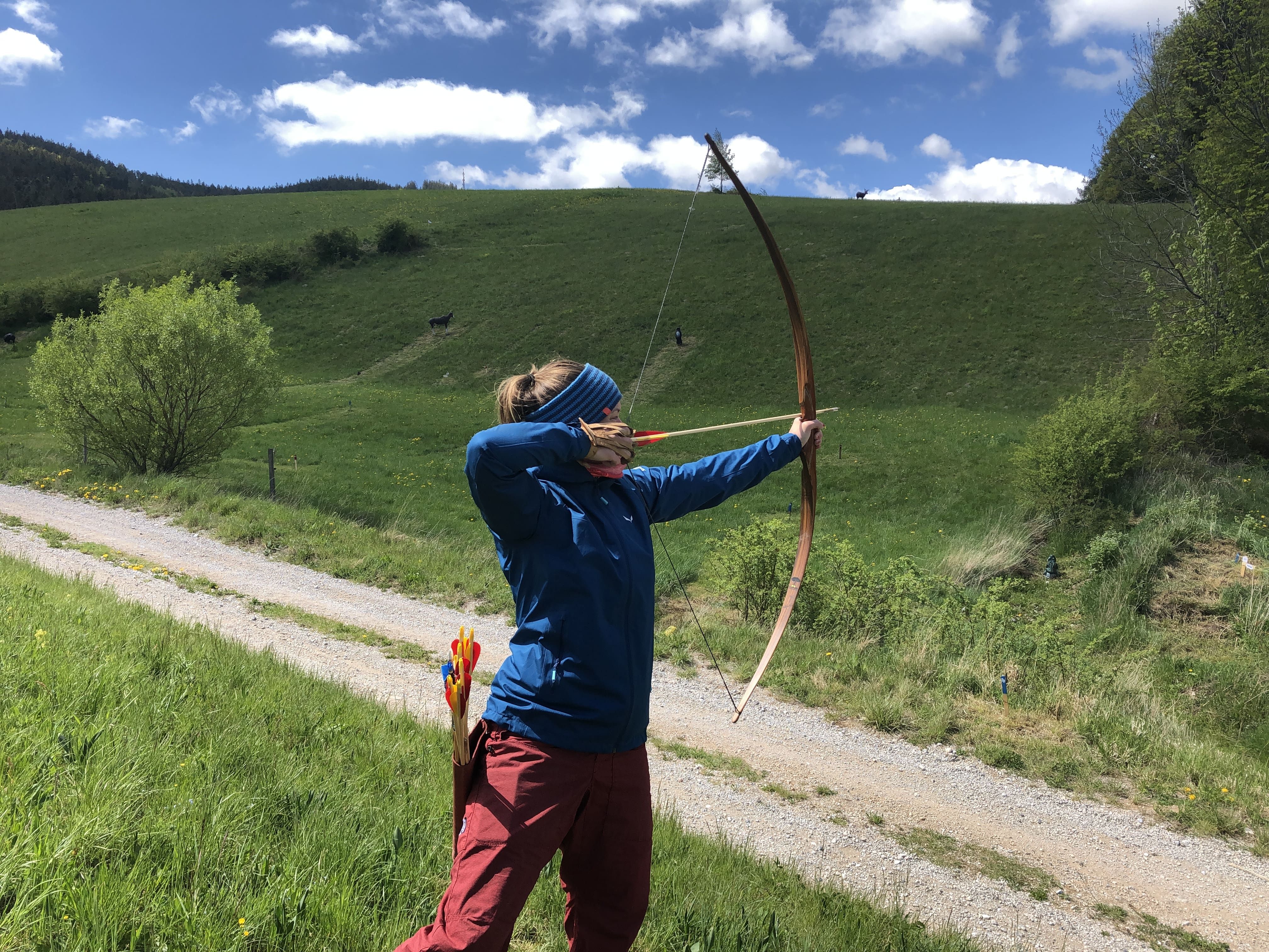 Person schießt mit einem Bogen auf einem Feld.