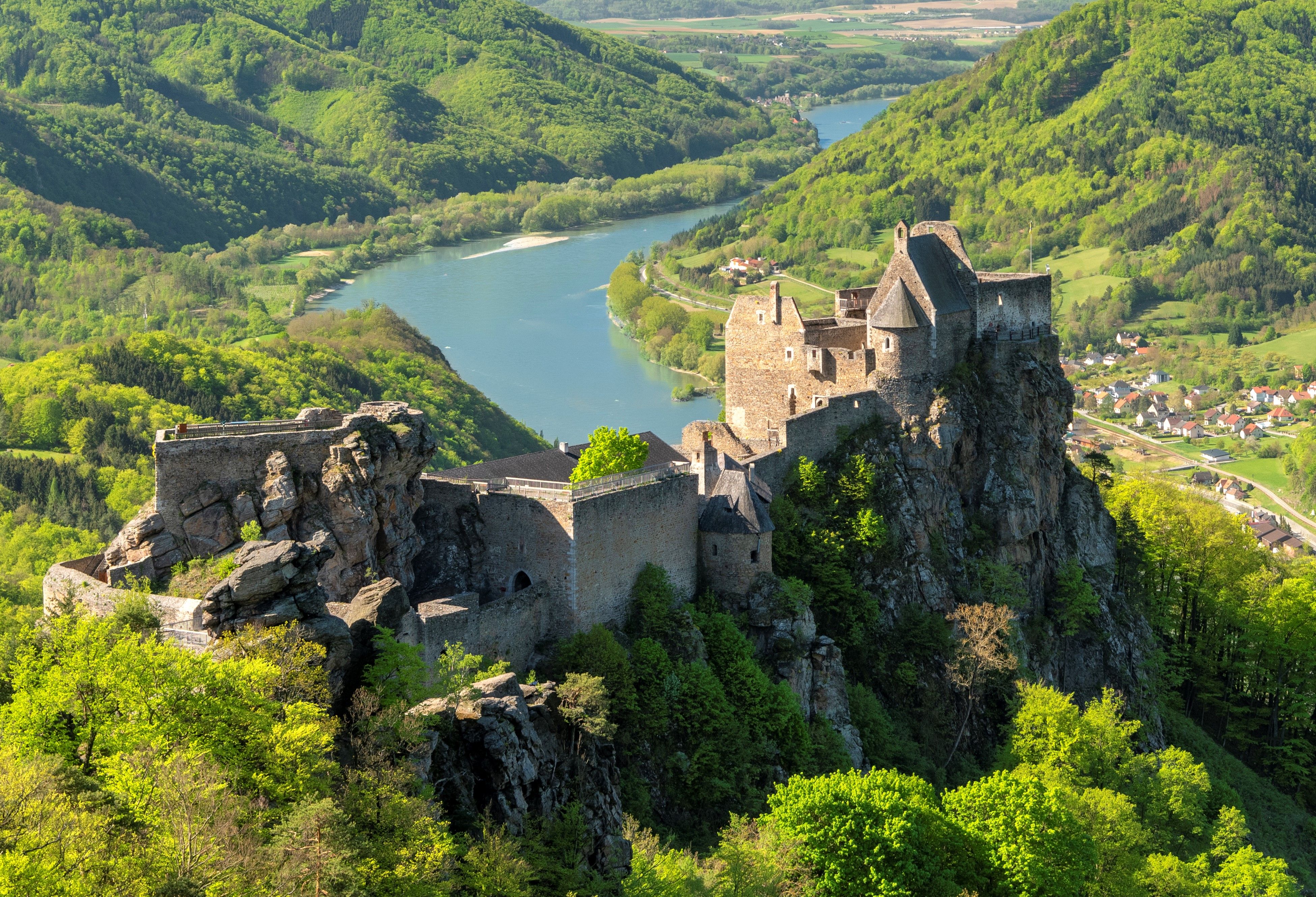 Die Burgruine Aggstein thront spektakulär auf einem Felsen hoch über der Donau und eröffnet einen beeindruckenden Panoramablick auf die Wachau mit ihren bewaldeten Hügeln und dem Flusstal.