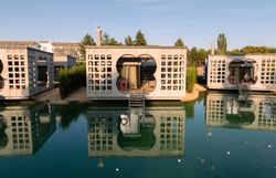 Moderne Villen auf Wasser mit reflektierenden Fassaden und Treppen, umgeben von Natur.