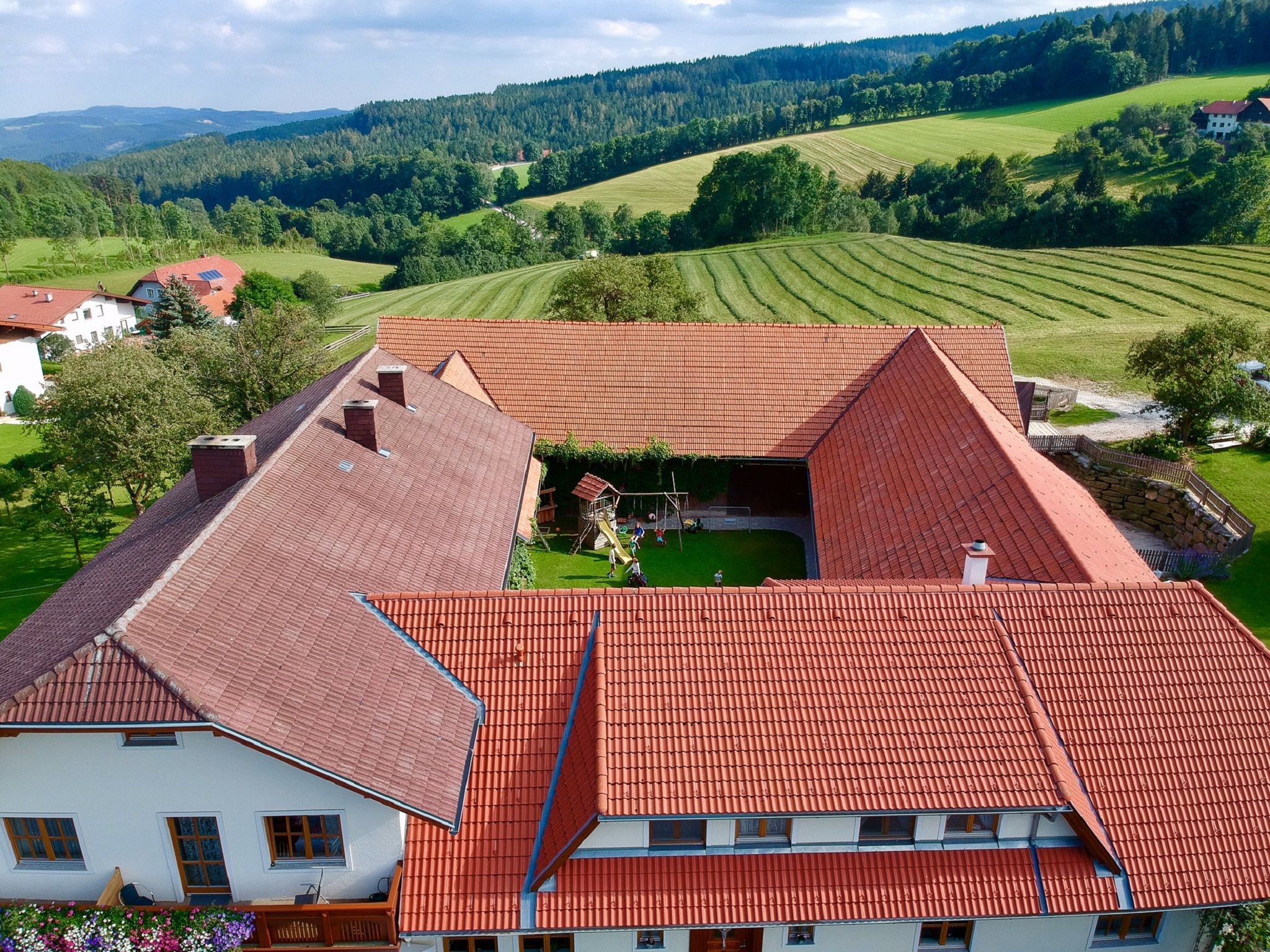 Luftaufnahme eines Bauernhofs mit Innenhof und umliegender Landschaft.