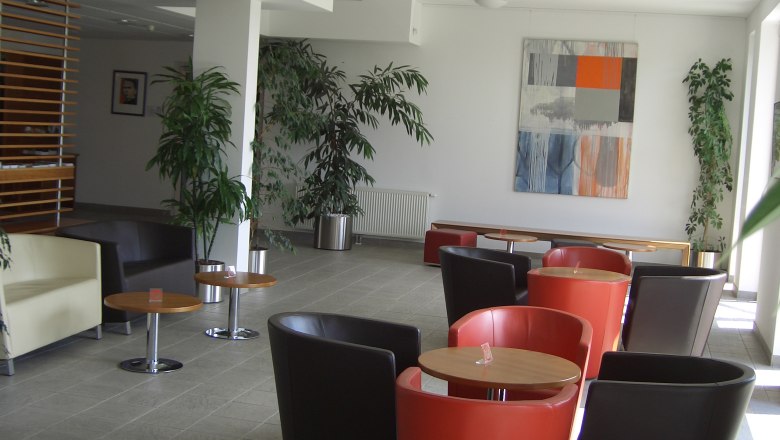 Moderner Aufenthaltsraum mit bunten Sesseln und Pflanzen.