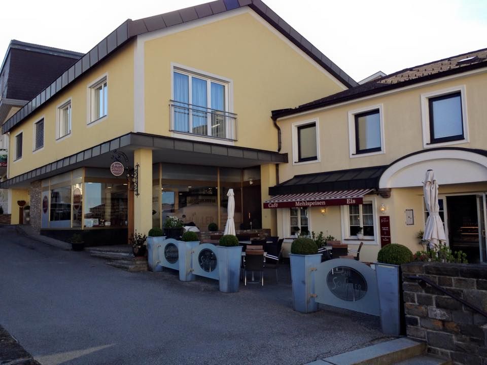 Gelbes Gebäude mit Café und Terrasse, Schüller Schriftzug sichtbar.