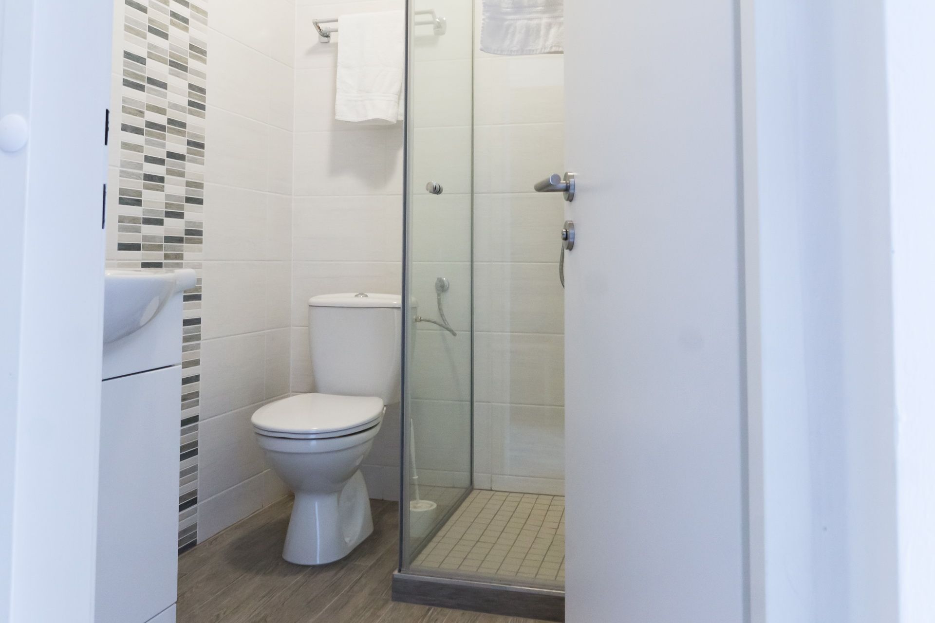 Modernes Badezimmer mit Toilette, Dusche und Handtuchhalter.