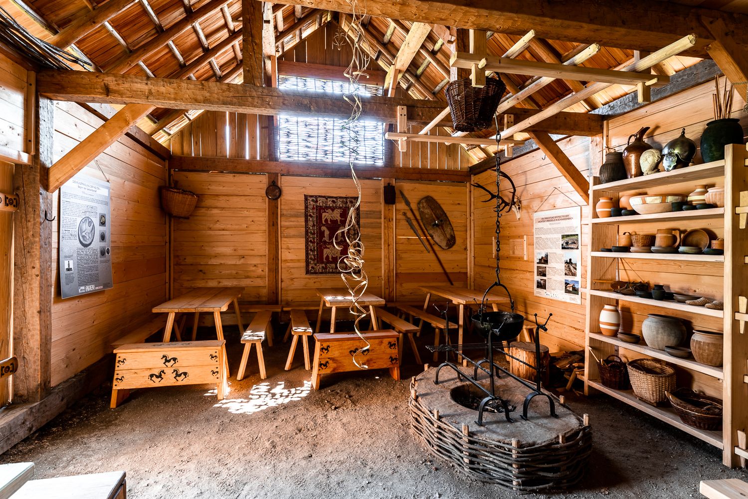 Innenansicht eines rekonstruierten keltischen Hauses mit Holzmöbeln und Töpferwaren.