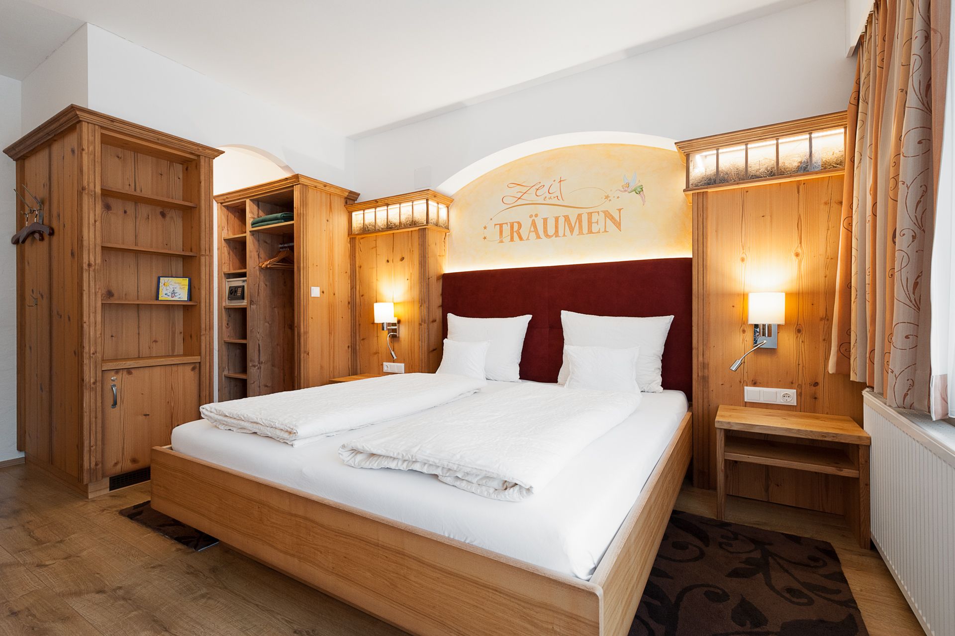 Gemütliches Schlafzimmer mit Holzmöbeln, Doppelbett und Schriftzug 'Zeit zum Träumen' an der Wand.