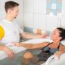 Eine Frau in einem Schwefelbad wird von einem Therapeuten betreut.