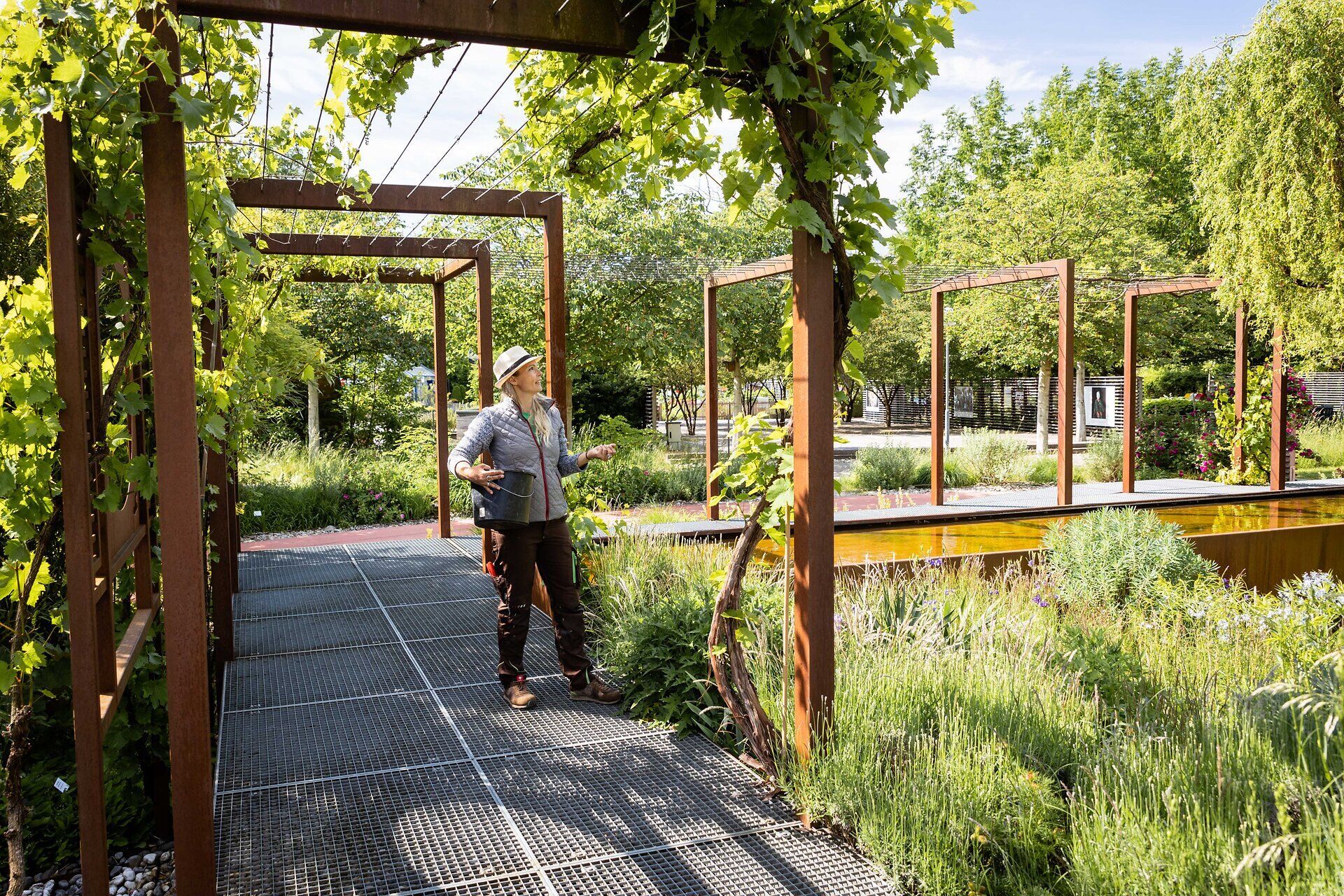 Inmitten einer blühenden Oase aus bunten Blumen und üppigem Grün entfaltet sich ein harmonischer Garten, der zum Verweilen einlädt. Die sanften Wege, gesäumt von Weinreben und duftenden Kräutern, schaffen eine Atmosphäre der Ruhe und Entspannung. Hier erleben Besucher die Schönheit des Frühlings in voller Pracht.