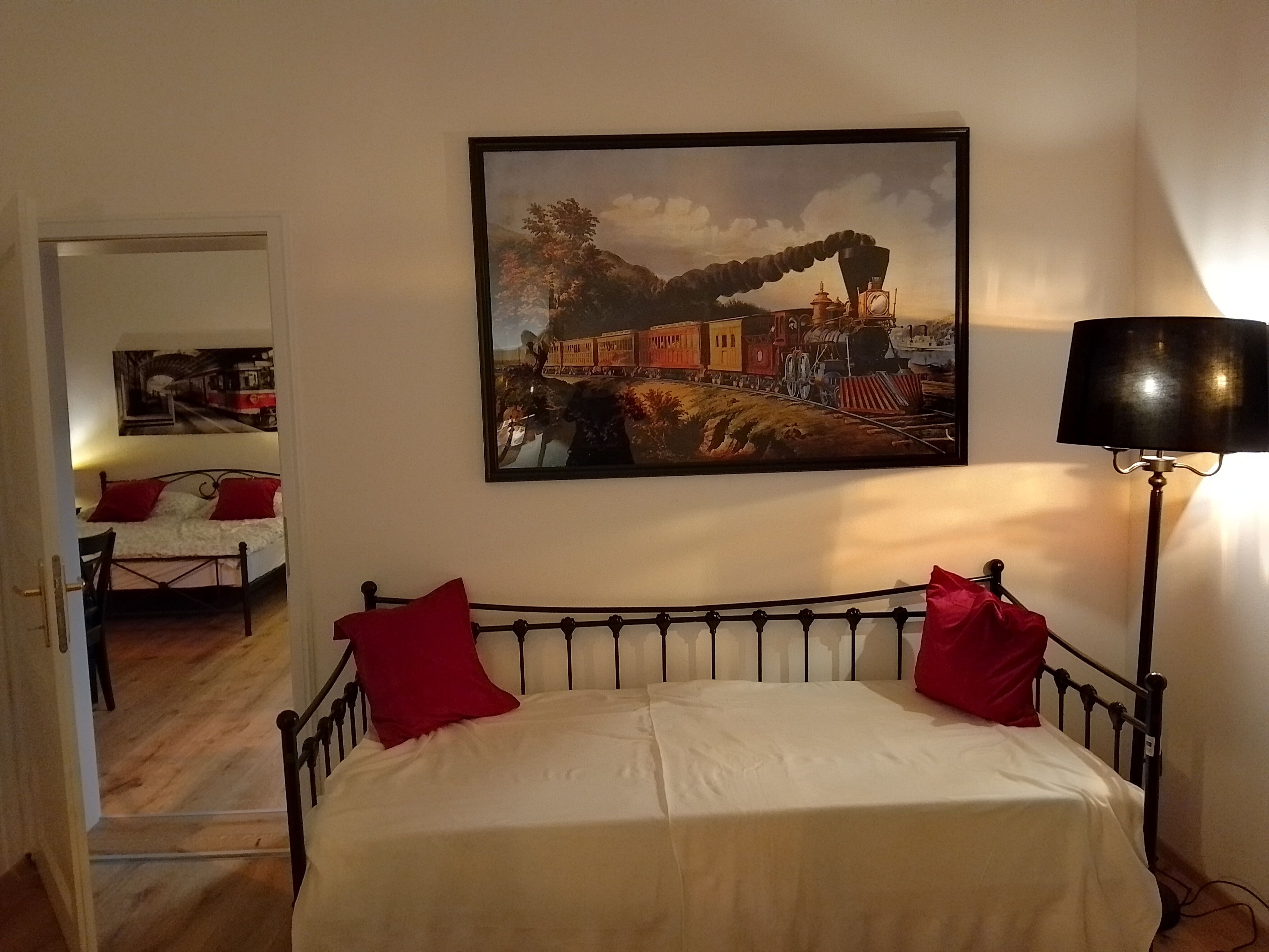 Zimmer mit Eisenbahndekor, Bett und Lampe.