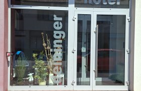 Eingang des Hotel Deininger mit Glasfront und Pflanzen.