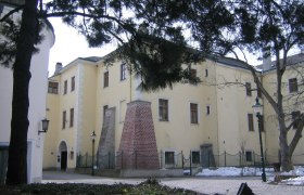 Schloss Purkersdorf im Winter mit schneebedecktem Boden und B&auml;umen im Vordergrund.