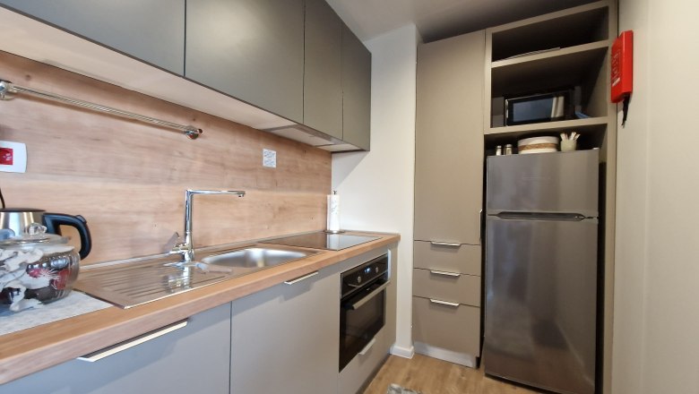 Moderne K&uuml;che mit grauen Schr&auml;nken, Edelstahlsp&uuml;le, Herd und K&uuml;hlschrank.