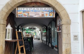 Eingang zur Citypassage mit Schildern für ein Bistro und eine Bar.