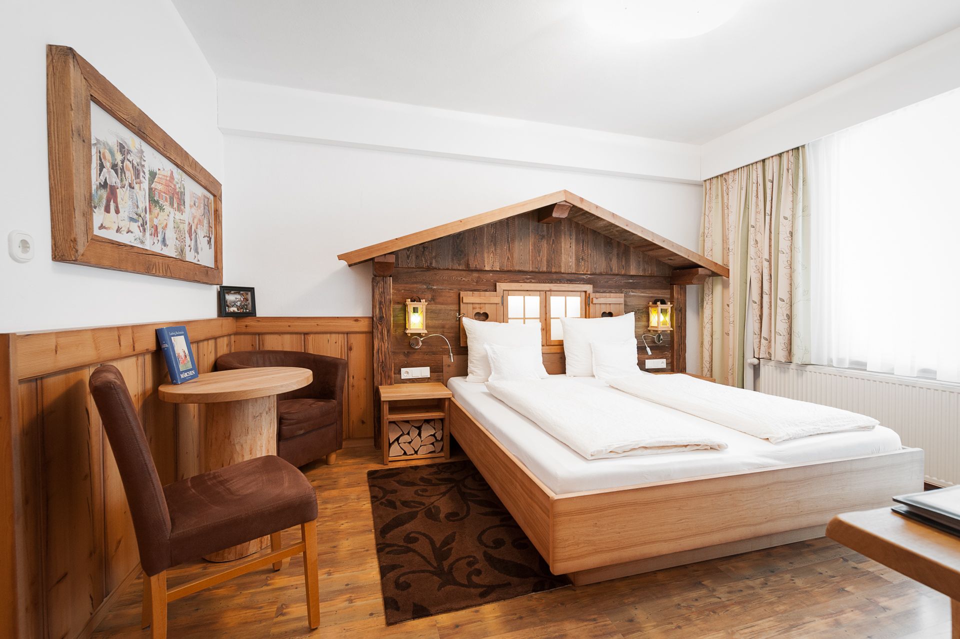 Gemütliches Hotelzimmer im Stil von Hänsel und Gretel mit Holzmöbeln und dekorativem Bettkopfteil.