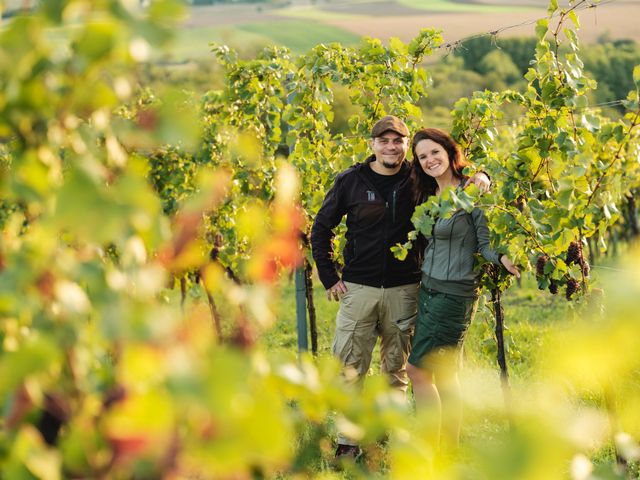 Ein Mann und eine Frau stehen lächelnd in einem Weinberg.