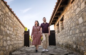 Paar spaziert durch das R&ouml;mische Stadtviertel der R&ouml;merstadt Carnuntum. Links und rechts Steinh&auml;user.