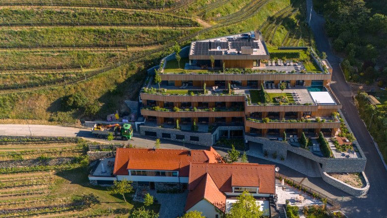 Weinhotel Nigl, © Niederösterreich Werbung / Maximilian Pawlikowsky Luftaufnahme eines modernen Hotels mit Terrassen und begrünten Dächern, umgeben von Weinbergen.