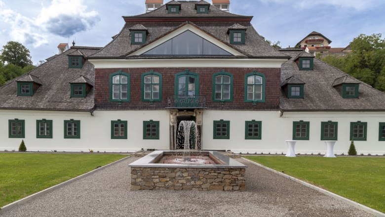 Au&szlig;enansicht von Schloss Luberegg mit Brunnen im Vordergrund.