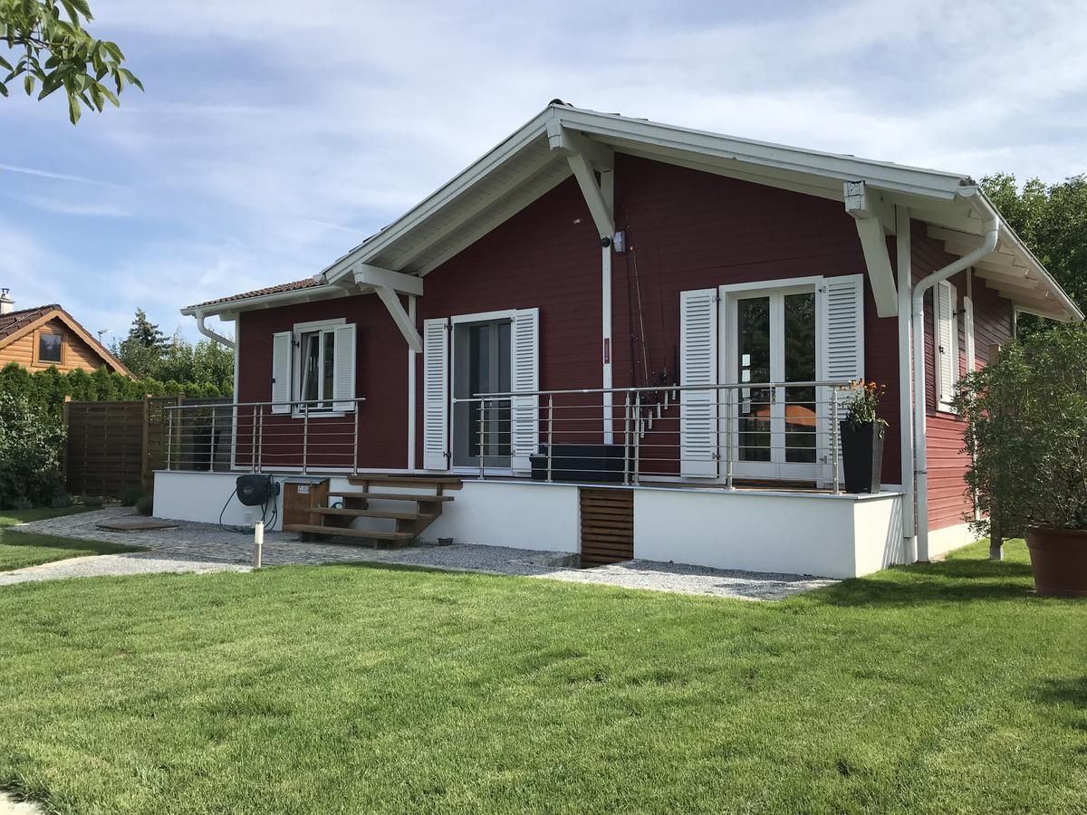 Ein rotes Holzhaus mit weißem Dach und Fensterläden, umgeben von einem gepflegten Garten.