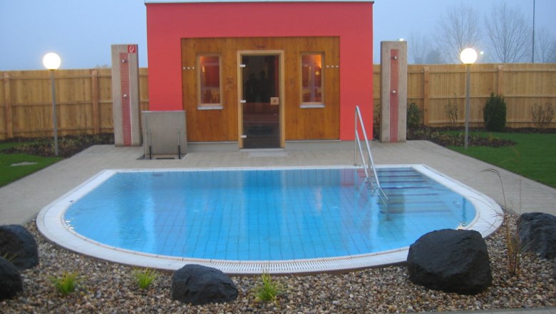 Au&szlig;enansicht einer Sauna mit kleinem Pool und Garten.