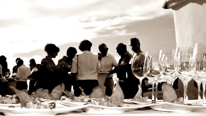 Menschen bei einer Veranstaltung im Freien mit Weingl&auml;sern und Snacks auf einem Tisch.
