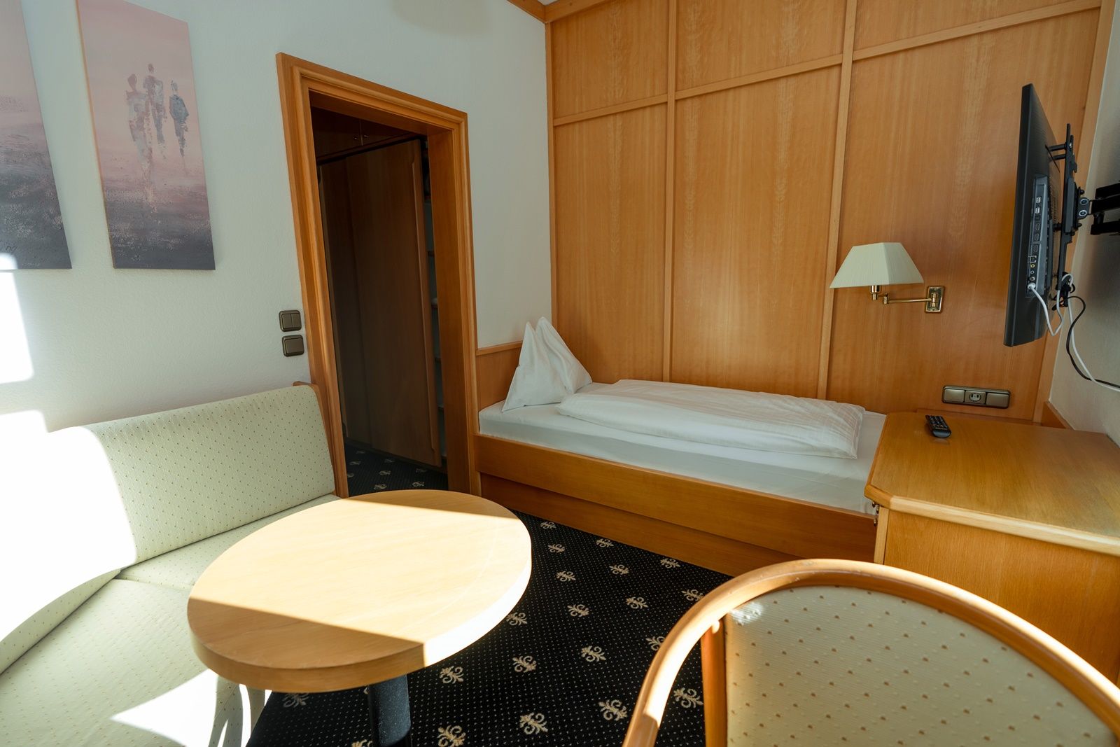 Einzelzimmer mit Bett, Sofa, Tisch und Fernseher.