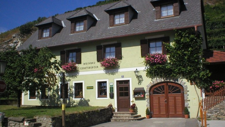 Au&szlig;enansicht eines Weinguts mit gelber Fassade und Blumen.