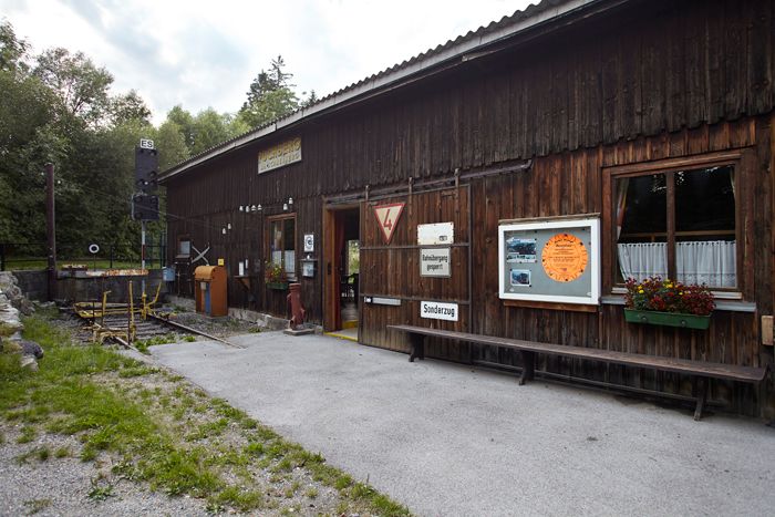 Holzgebäude mit Schildern und Blumen, Teil einer Ausstellung.