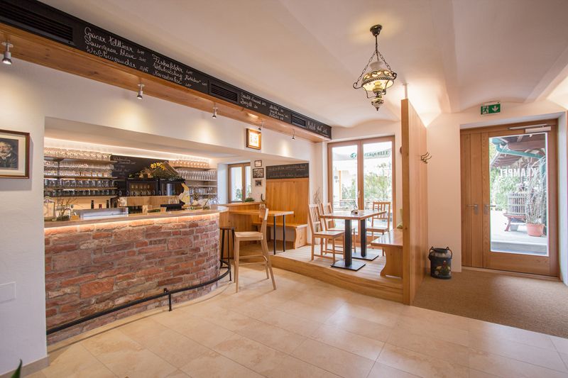 Innenansicht einer gemütlichen Weinbar mit Holzmöbeln und Ziegeltheke.