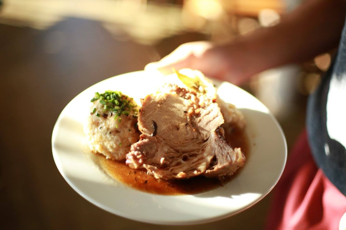 Ein Teller mit Braten, Knödel und Soße.
