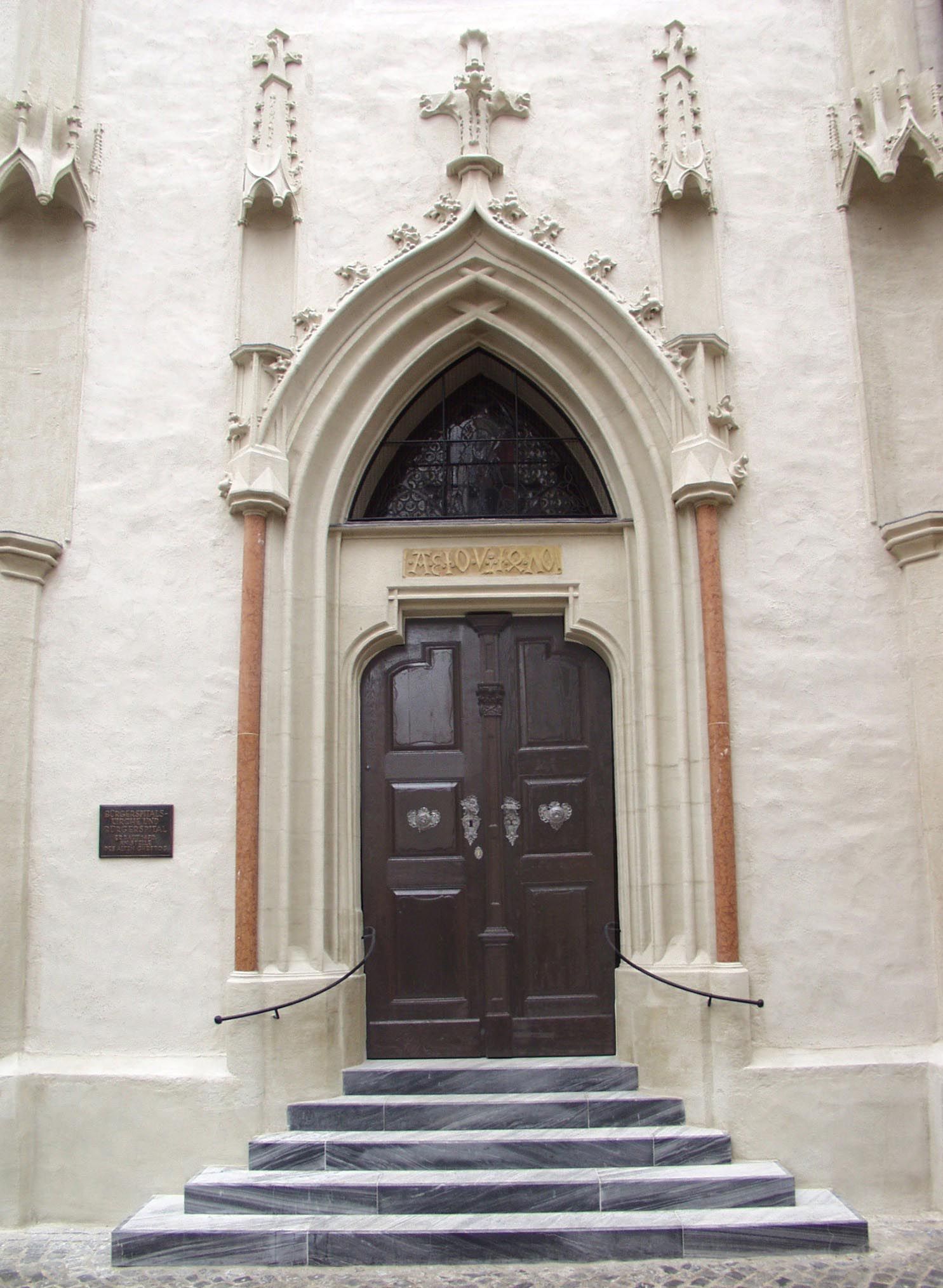 Eingang der Bürgerspitalskirche mit gotischem Portal und Holztür.