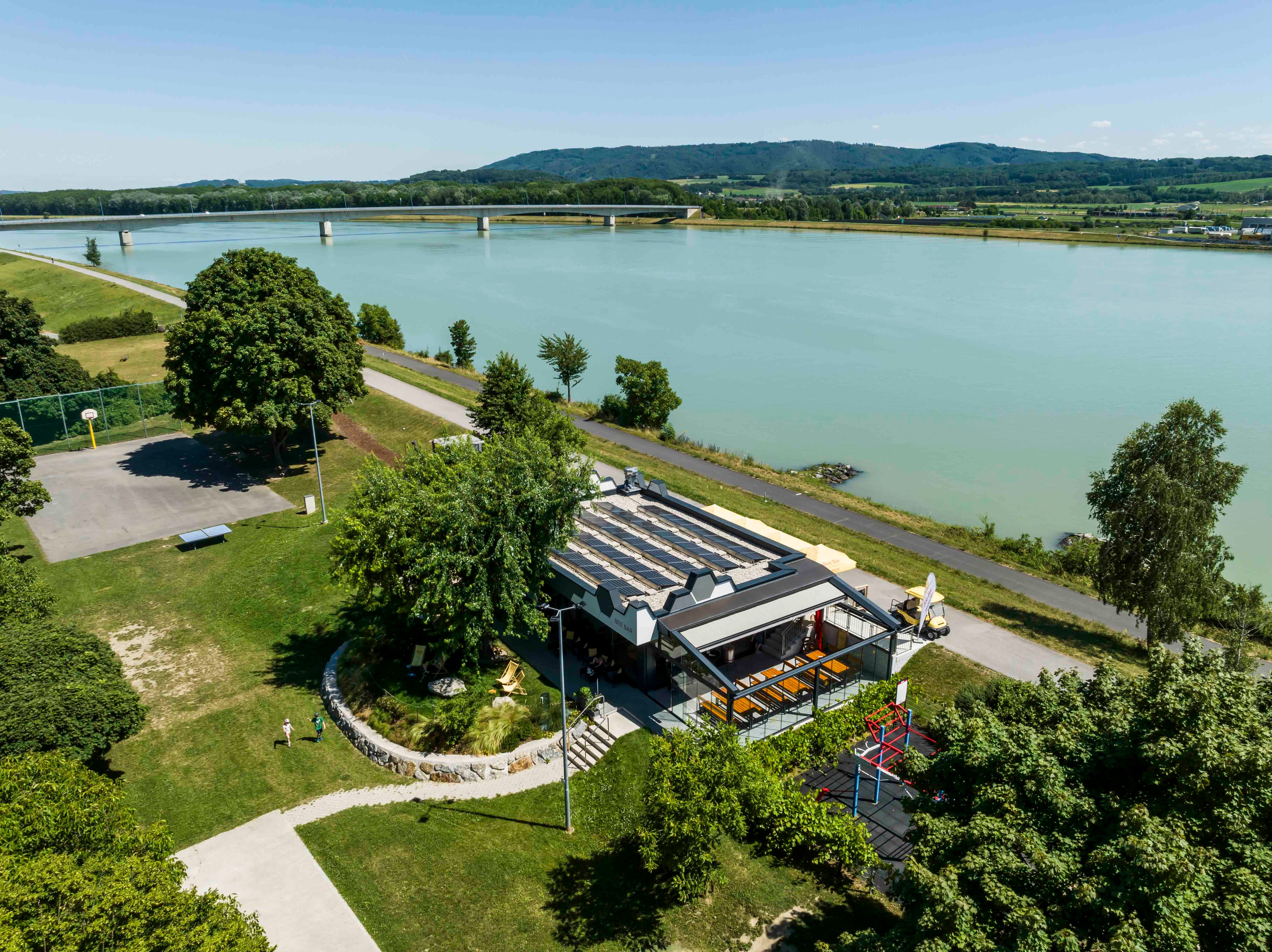 Luftaufnahme der Bee-Bar in Klein-Pöchlarn am Flussufer mit umliegender Landschaft.