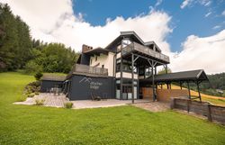 Ötscher Lodge in einer grünen, bewaldeten Umgebung mit blauem Himmel.