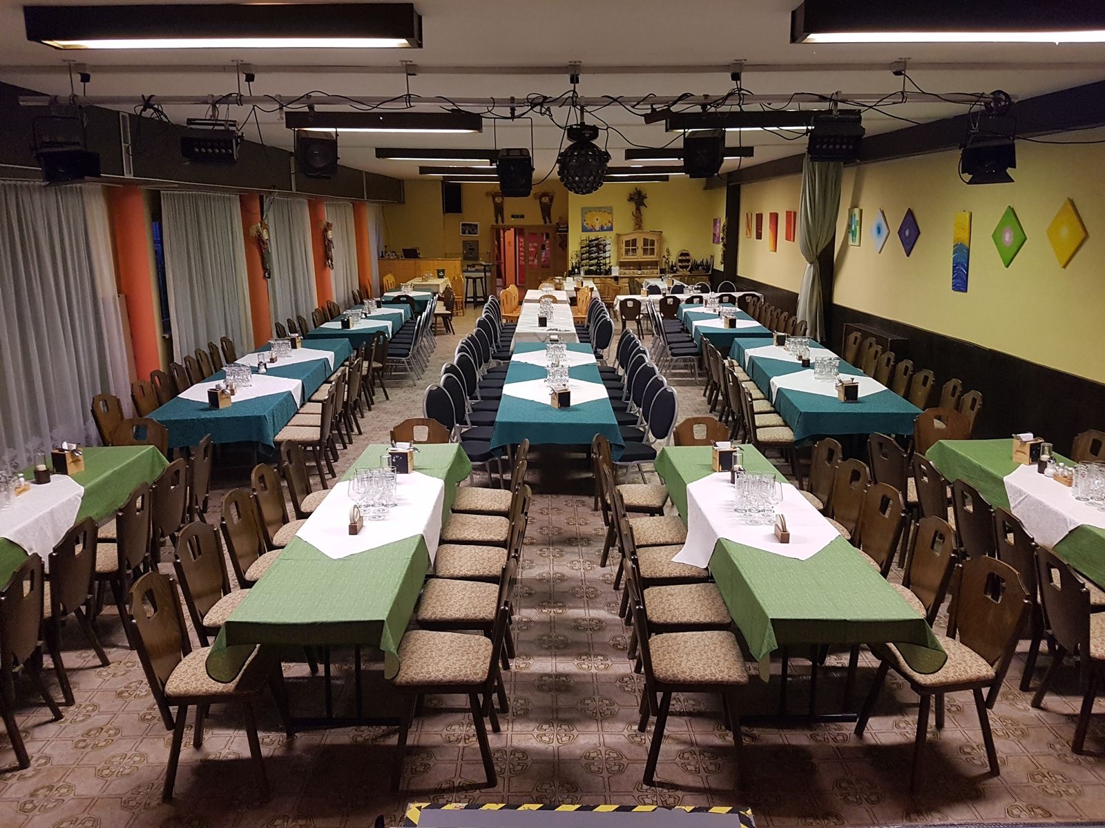 Ein großer Saal mit langen, gedeckten Tischen und Stühlen, bereit für eine Veranstaltung.