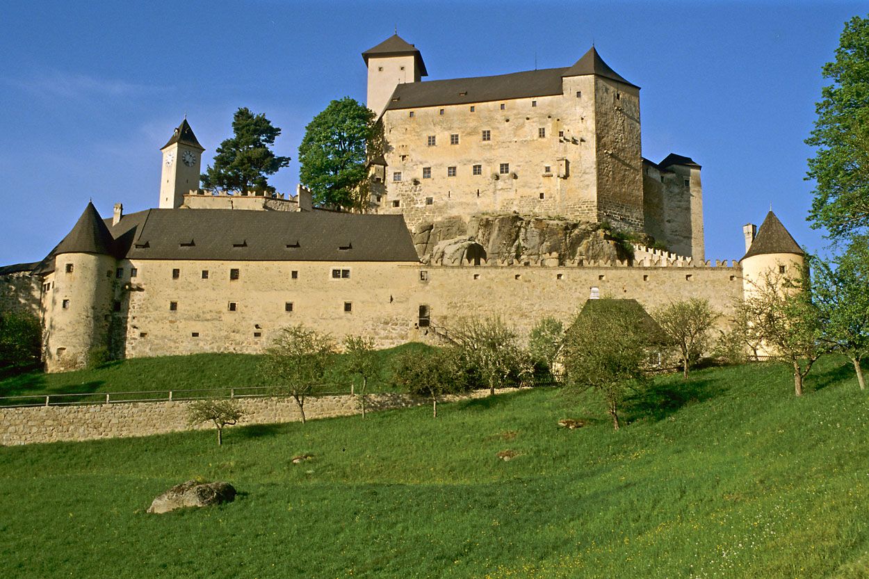 Burg Rappottenstein auf einem Hügel mit grüner Wiese im Vordergrund.