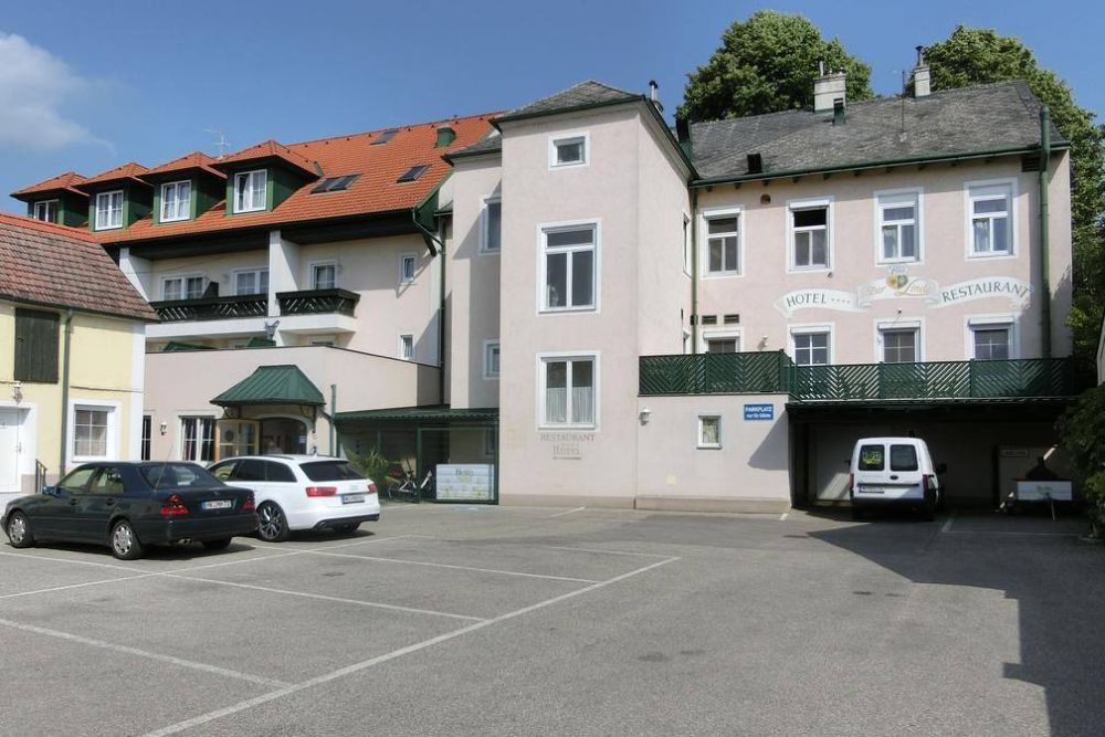 Außenansicht eines Hotels mit Parkplatz und Autos.