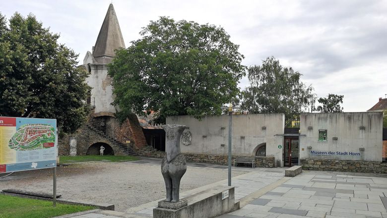 Stadtmauer und Museum in Horn mit Statue und Infotafel im Vordergrund.