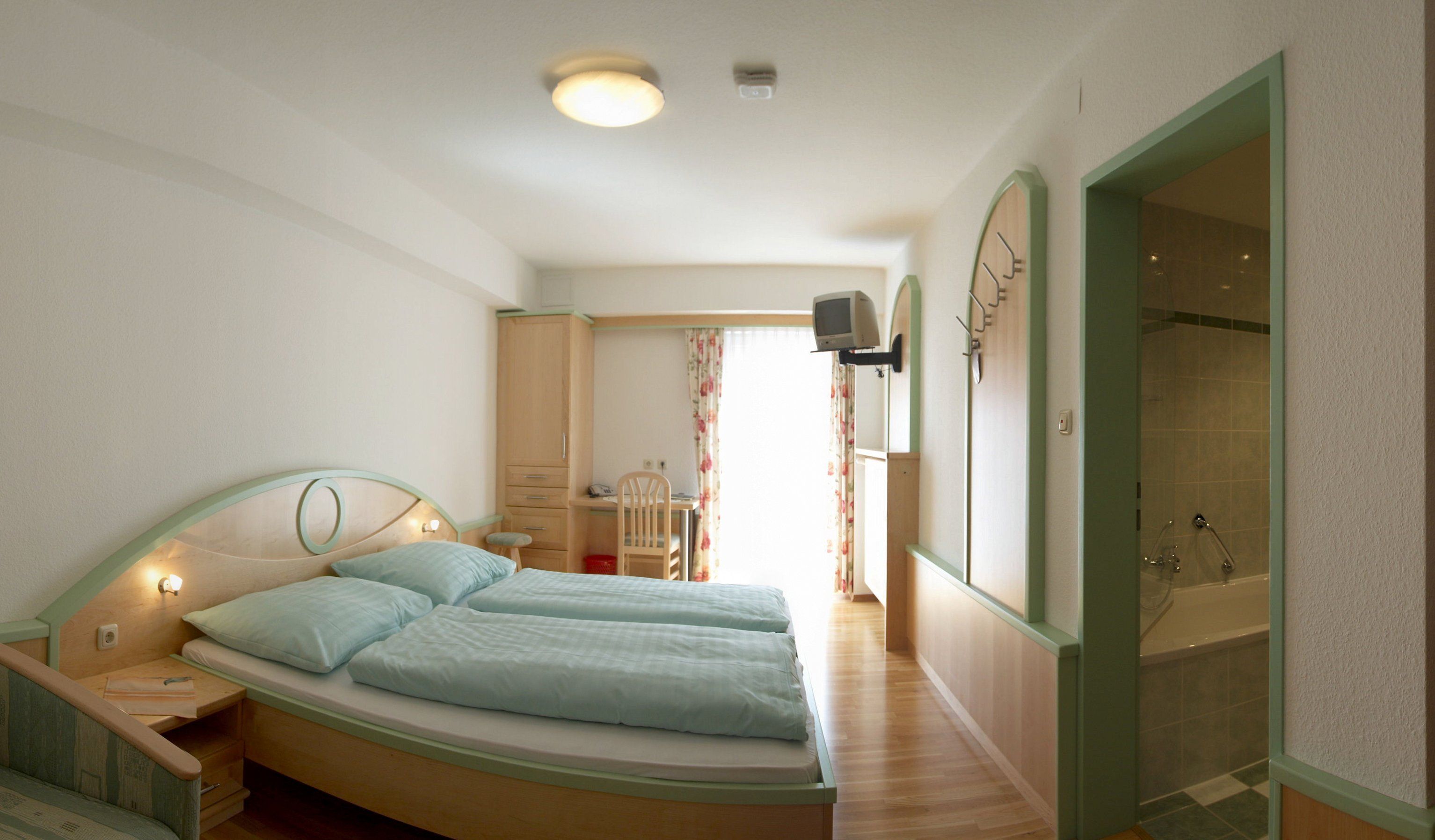 Ein Hotelzimmer mit Doppelbett, Schreibtisch, Fernseher und Badezimmer.