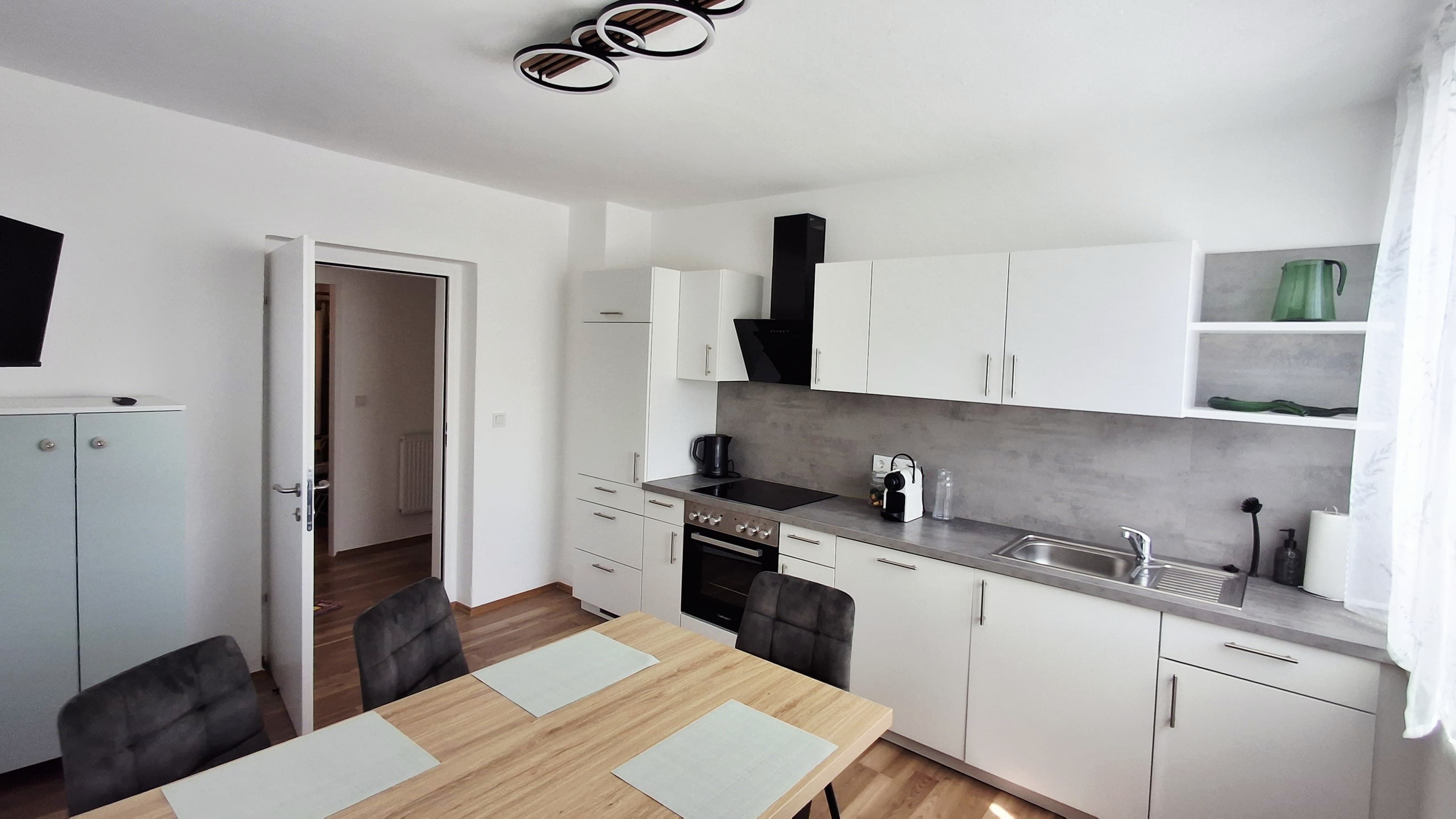Moderne Küche mit weißen Schränken, Esstisch und Stühlen im Gästehaus Iwanestal.