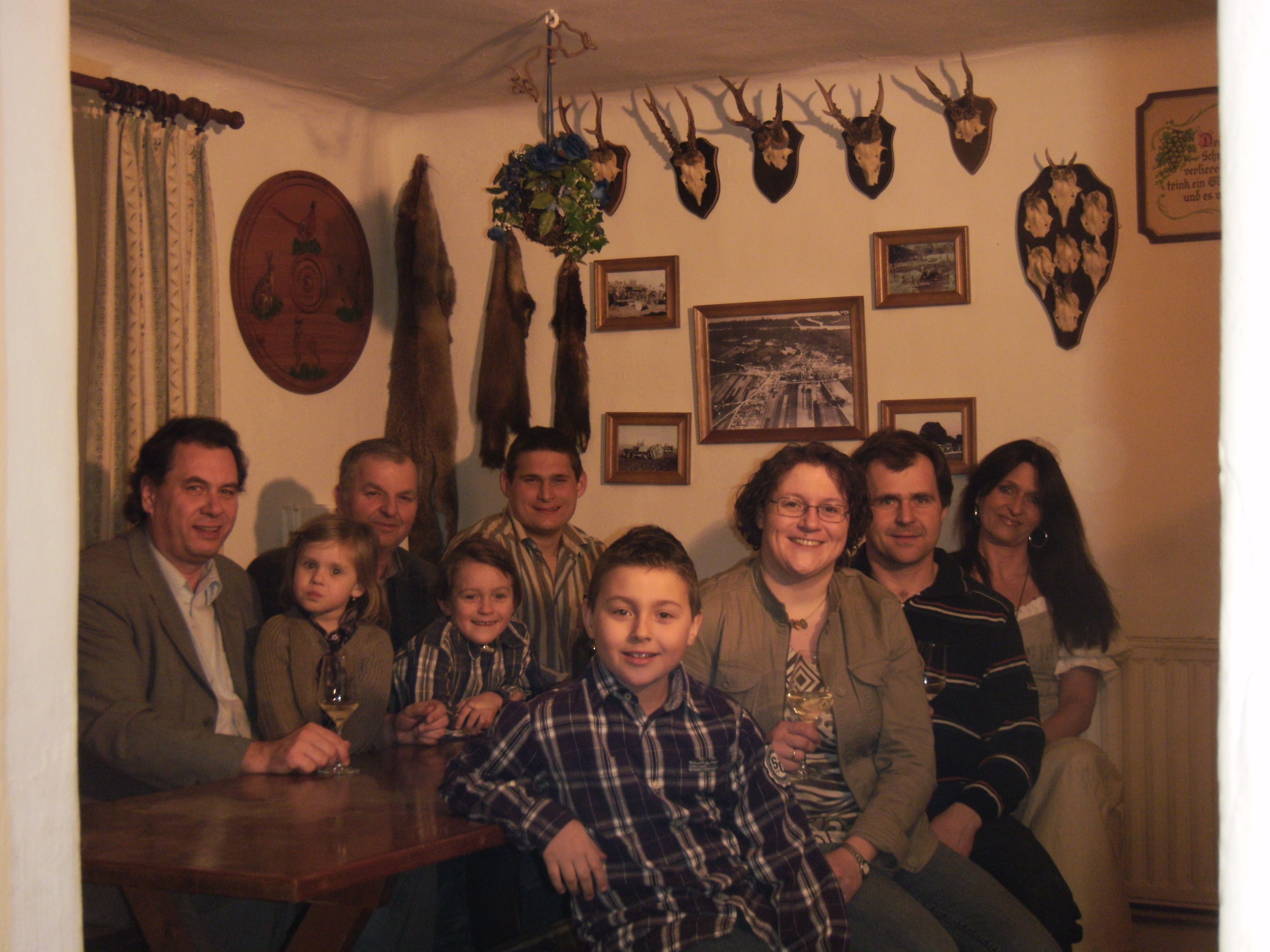 Eine Gruppe von Menschen sitzt in einem Raum mit Jagdtrophäen an der Wand.
